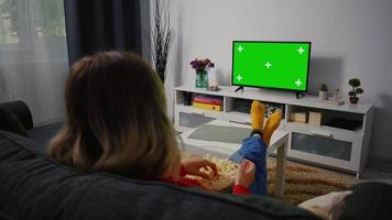 kvinna tittar på grön chroma key screen tv, avkopplande. video