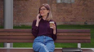mujer de negocios hablando por teléfono móvil y sosteniendo una taza de café. video