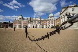 Metallic barbed wire fence in front of Old Building - thin and sharp iron object used for private property security. photo