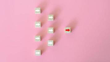 Leadership concept. The white arrows on wooden blocks and red arrows lead the way on pink background. Business start-up. Different thinking for discovering new technology and business opportunity. photo