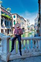 A Venice gondolier sitting on a bridge waits for customers photo