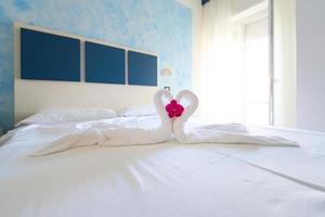 Heart of swans kissing on the bed of a holiday hotel room prepared by waitress with wipes photo