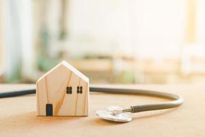Home repair and inspector concept. Stethoscope and wooden home model. Checking house and real estate with sunlight. photo