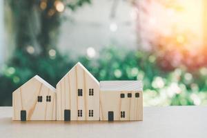 Eco home concept. Small wooden home model with green natural bokeh background with copy space. photo
