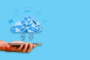 Cloud data storage concept. Hand-holding smartphone or mobile with Polygon cloud computing and icons transfer data on blue background. Communication of business and financial. photo