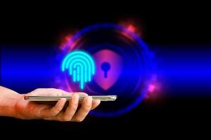 Fingerprint and security concept. Hand holding mobile or smartphone with virtual fingerprint and security background. Safety internet and network connection. photo