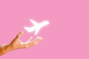 Hand and white plane draw on pink background. Travel concept. photo