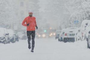 el hombre corre en la calle del centro de una ciudad nevada foto