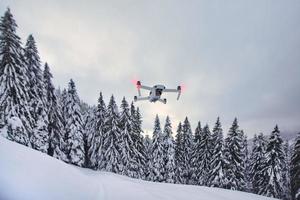 Drone just got up in flight after snowfall near trees photo
