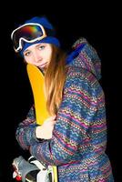 Young girl embraces her snowboard in studio on black background
