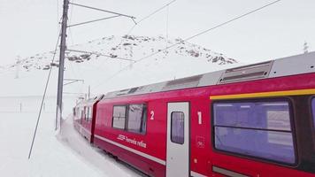 Red train in the Swiss Alps. Passage through the snow