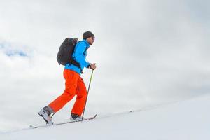 hombre con escalada de esquí de montaña hacia la cumbre foto