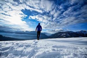 Solo excursion with snowshoes on a dark and sunny day photo