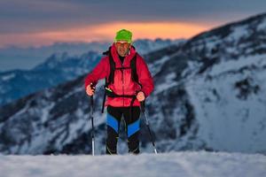 At sunset a ski touring uphill on the Alps photo