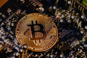 Physical Bitcoin coin resting on electronic circuits photo