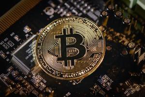 Physical Bitcoin coin resting on electronic circuits photo