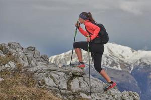 Girl in action uphill on steep trace of stones in the mountains photo