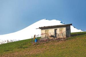 A shepherd  hermitage in the meadow with snow capped mountains behind photo