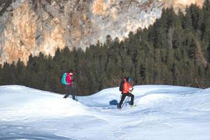 Pair of girls walks on snow with mountaineering equipment photo