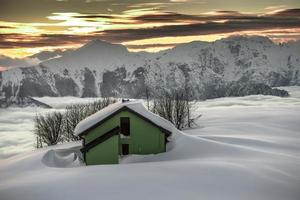 cabaña alpina en la nieve durante la puesta de sol foto