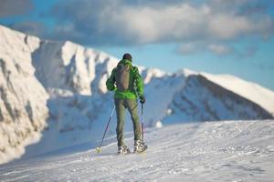 Mountaineer in winter landscape with snowshoes photo