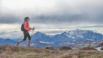 una chica de marcha nórdica caminando sola en las montañas foto