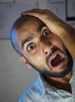 A bald young man shocked in front of camera photo