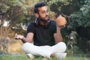 A man holds an earphone on his shoulder and deposit the money on his piggy bank photo