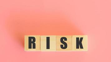 Risk assessment investment concept. Wooden block with risk word on pink background. Analysis and management of a business. photo