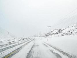 conduciendo a través de una tormenta de nieve con hielo negro en la carretera, noruega. foto