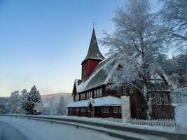 Red Norwegian Stave Church in winter landscape in Norway. photo