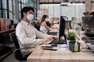 Three coworkers team, face mask colleagues working in new normal office. COVID-19 protection by cleared partition, business workplace office, social distancing for pandemic health, disease prevention. photo