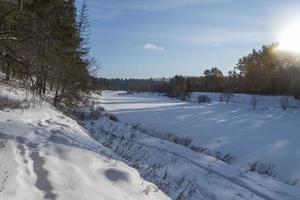río congelado cerca del bosque en un soleado día de invierno. foto