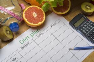 Diet plan, tape measure, water, diet of fresh fruits on the wooden floor. photo