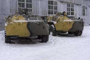 Two armored vehicles stand at the hangar on a winter day. photo