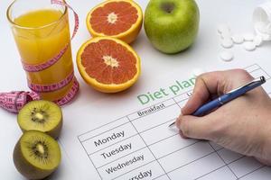 The doctor writes a prescription to the patient, makes a diet plan in the workplace with fresh fruit. photo