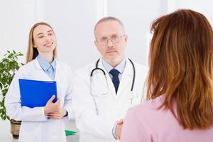 Doctor is talking with woman patient and sitting in medical office.Man in white uniform. Medical insurance. Copy space. Quality medicine concept. photo