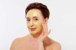 Middle age macro woman face. Summer anti aging collagen mask on woman wrinkle face isolated on white background. Spa and menopause concept. Copy space photo