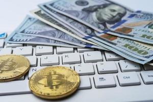 Bitcoin coin with keyboard and US dollars. Bitcoin gold coins on dollar banknotes office with a white background.