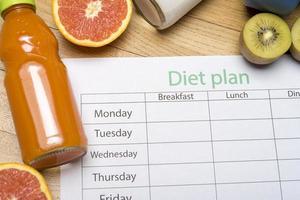 Diet plan, tape measure, water, diet of fresh fruits on the wooden floor. photo