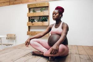 mujer embarazada negra haciendo yoga y meditación