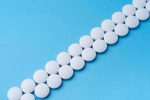 White medical pills on a blue background diagonally. photo