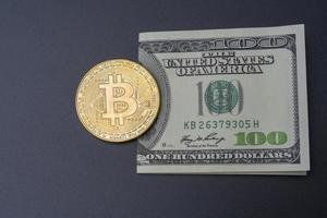 One hundred dollars and bitcoin on a black background. photo