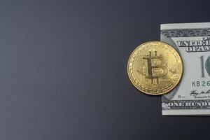 One hundred dollars and bitcoin on a black background. photo