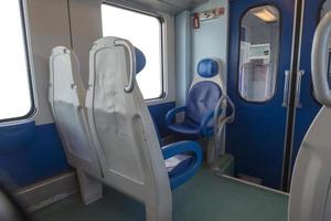 dentro de la cabina del expreso moderno. nadie en sillas azules junto a la ventana. borrosidad. cómodas sillas y mesa en primer plano, fondo blanco fuera de la ventana. foto