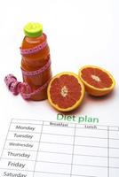 Diet plan and bottle of grapefruit juice with fresh grapefruit on white background. photo