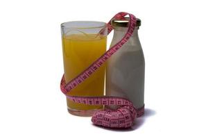 jugo de naranja fresco en un vaso y una botella de yogur con un centímetro sobre un fondo blanco aislado. foto