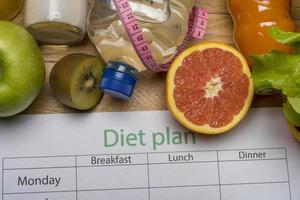 Diet plan, tape measure, water, diet of fresh fruits on the wooden floor. photo