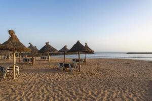 Empty sunbeds at a tropical beach. Sun loungers on the sandy beach by the sea. Summer vacation and vacation concept for tourism. photo