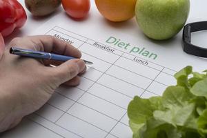 The doctor writes a prescription to the patient, makes a diet plan in the workplace with fresh fruit. photo